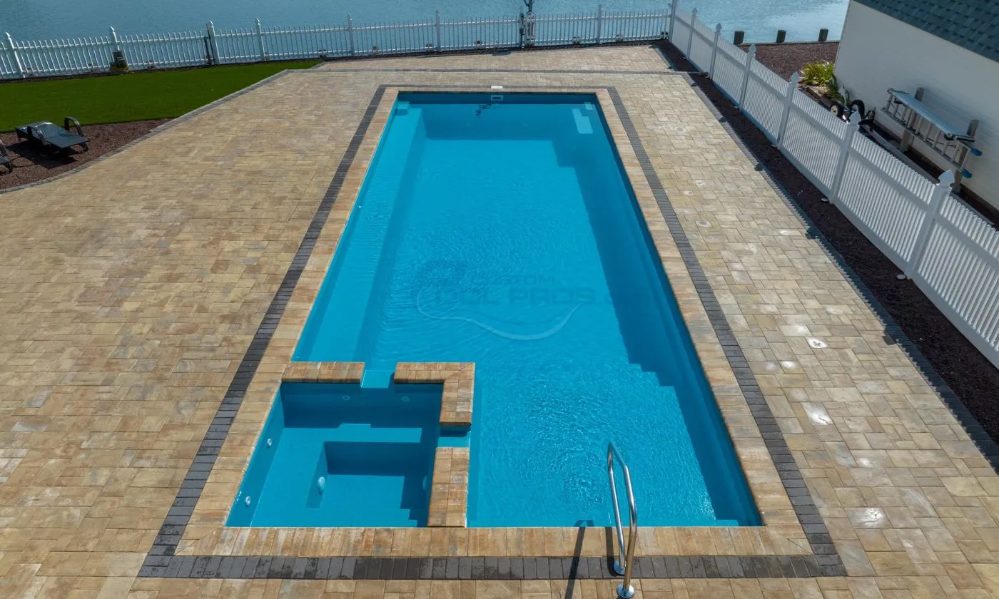 Luxury outdoor swimming pool with clear blue water, surrounded by a tiled deck and a grassy area, ideal for relaxation and leisure activities.