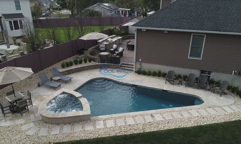 custom triangular freeform inground pool installation with matching spa in backyard, pool companies in nj