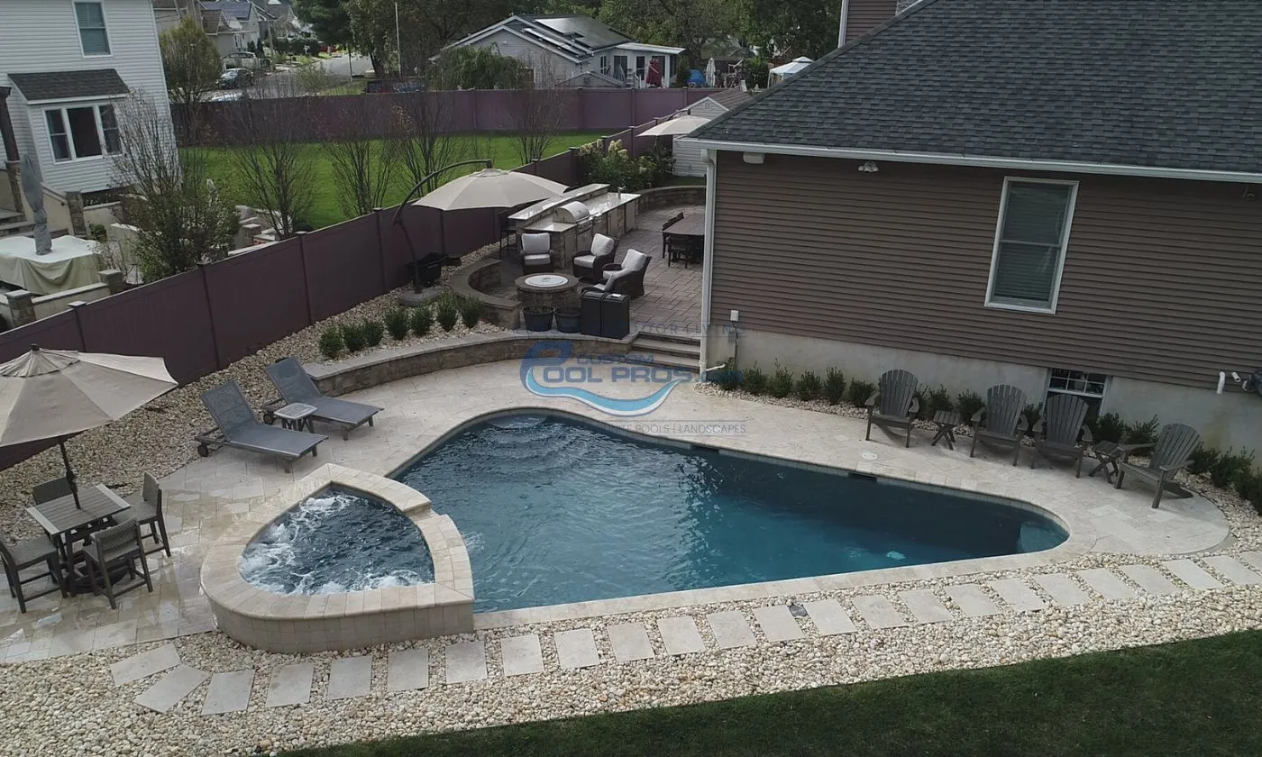 custom triangular freeform inground pool installation with matching spa in backyard, pool companies in nj
