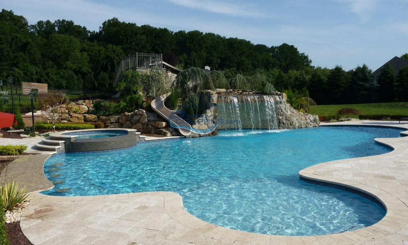 freeform inground pool with spa, waterfall grotto, slide, shallow area, pool deck with travertine tile installation, modern swimming pool, swimming pool companies in new jersey