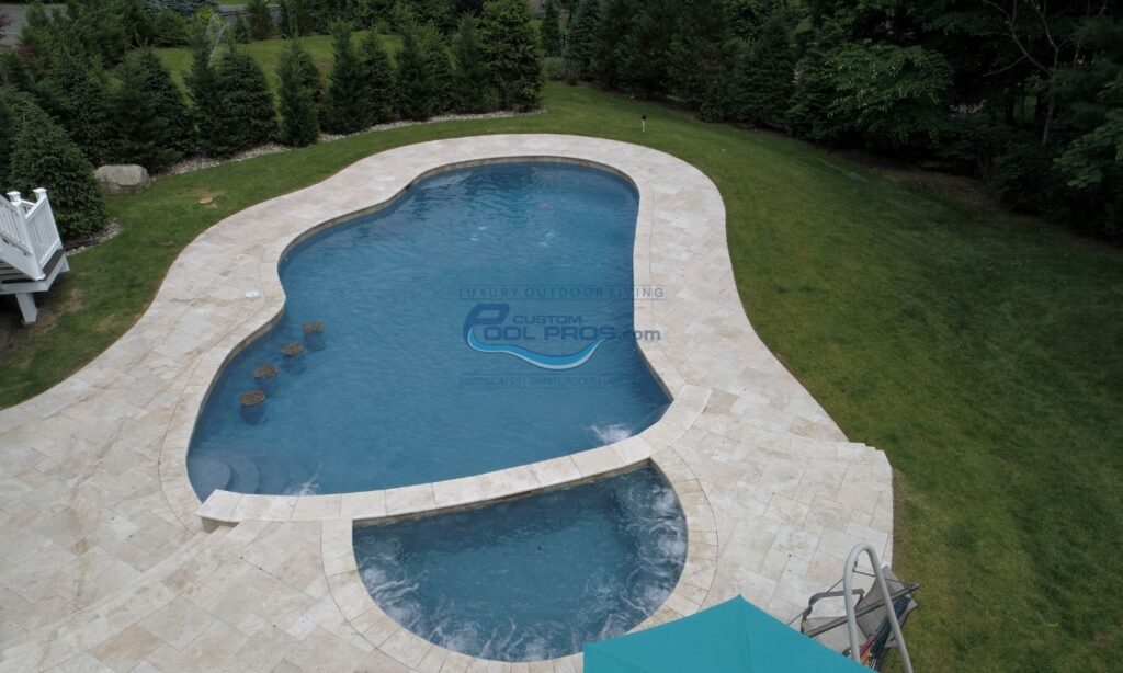 freeform inground gunite concrete pool with 4 in water seat stools, spa with jets turned on, pool deck built with travertine tile, pool installation nj