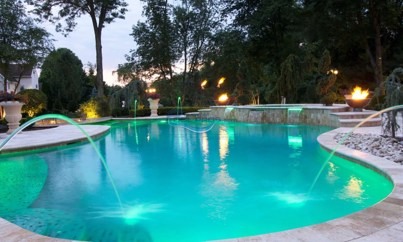 freeform inground pool installation with lights, water jets, water falls, gas fire bowls, bull nose coping and travertine pool deck