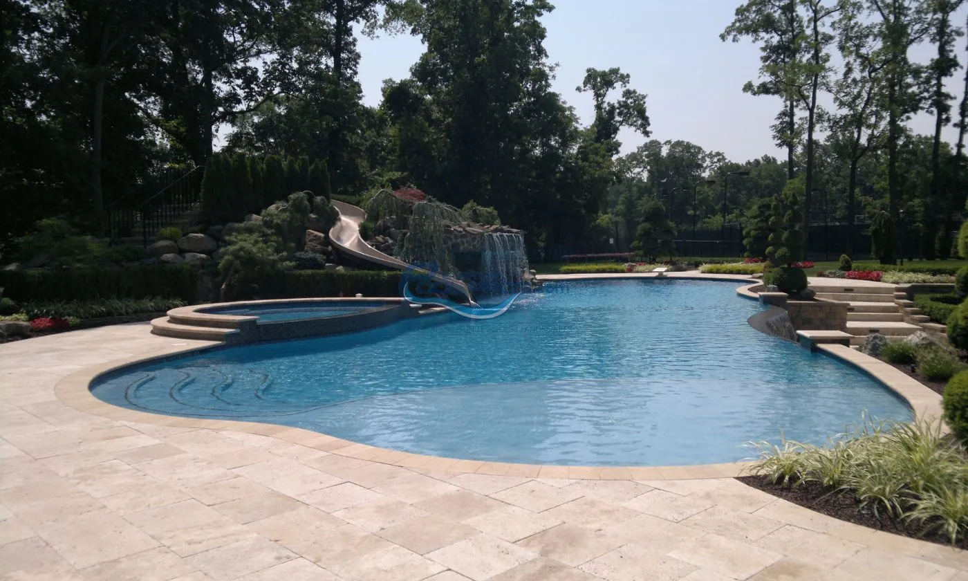 inground pool with spa, waterfall grotto, slide and vanishing edge, travertine pool patio deck installation, pool company nj