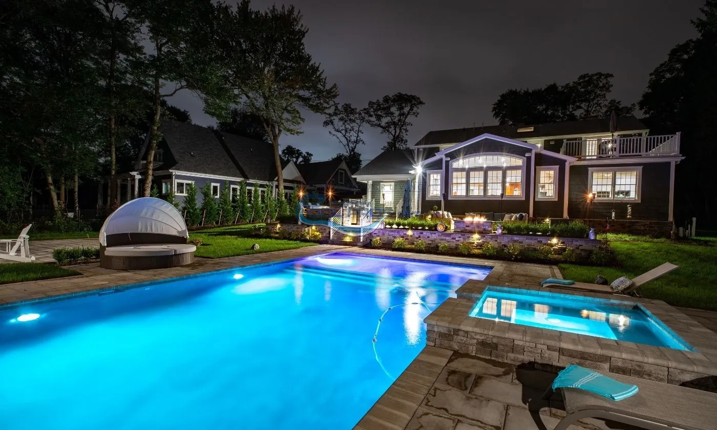 backyard pool and spa installation at night with pool lights on