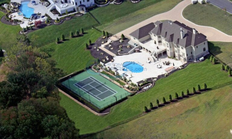 custom inground freeform pool with large patio and tennis court in backyard of a large house, custom inground pool