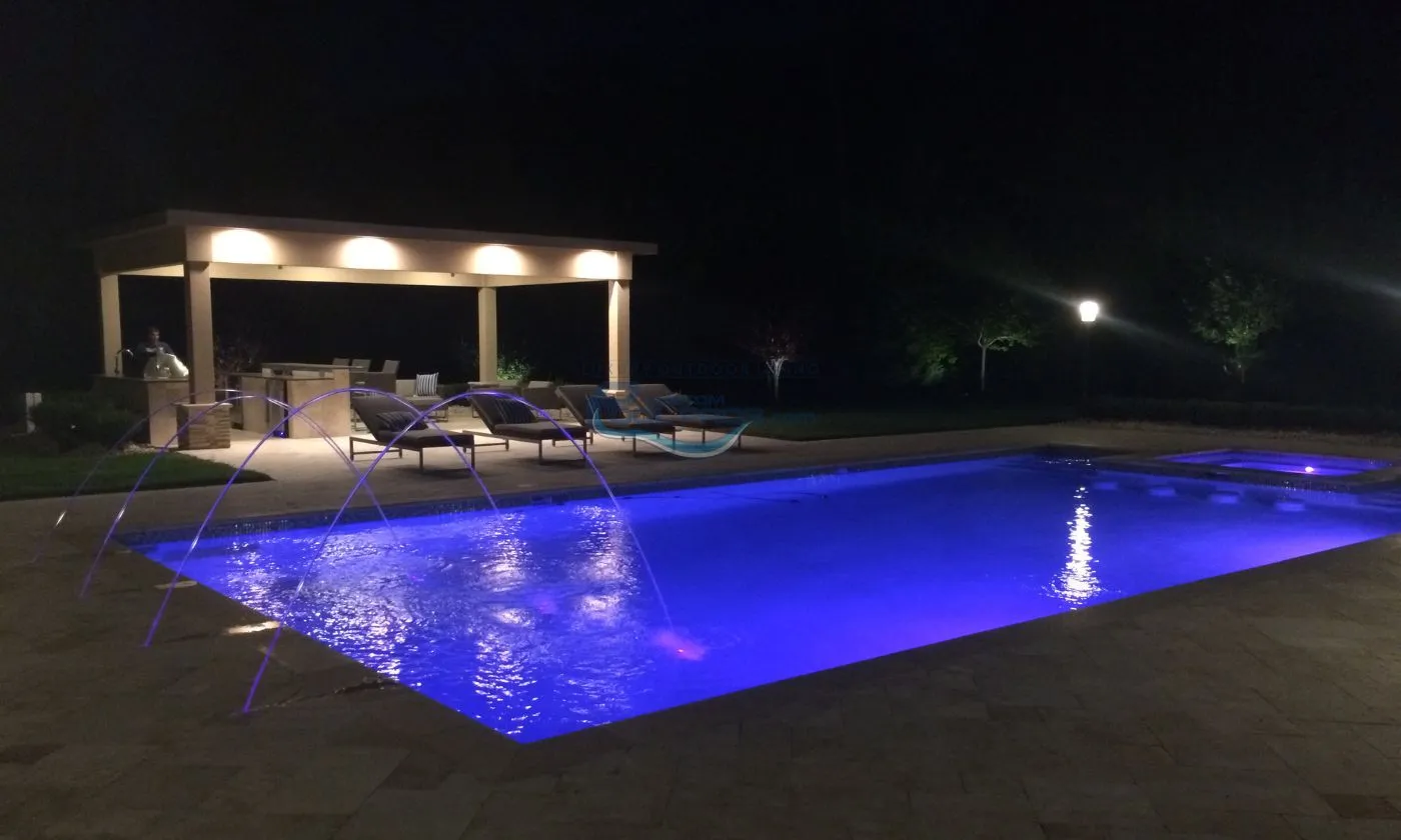 rectangular inground pool at night with pool lights, water jets and pavilion, inground pool